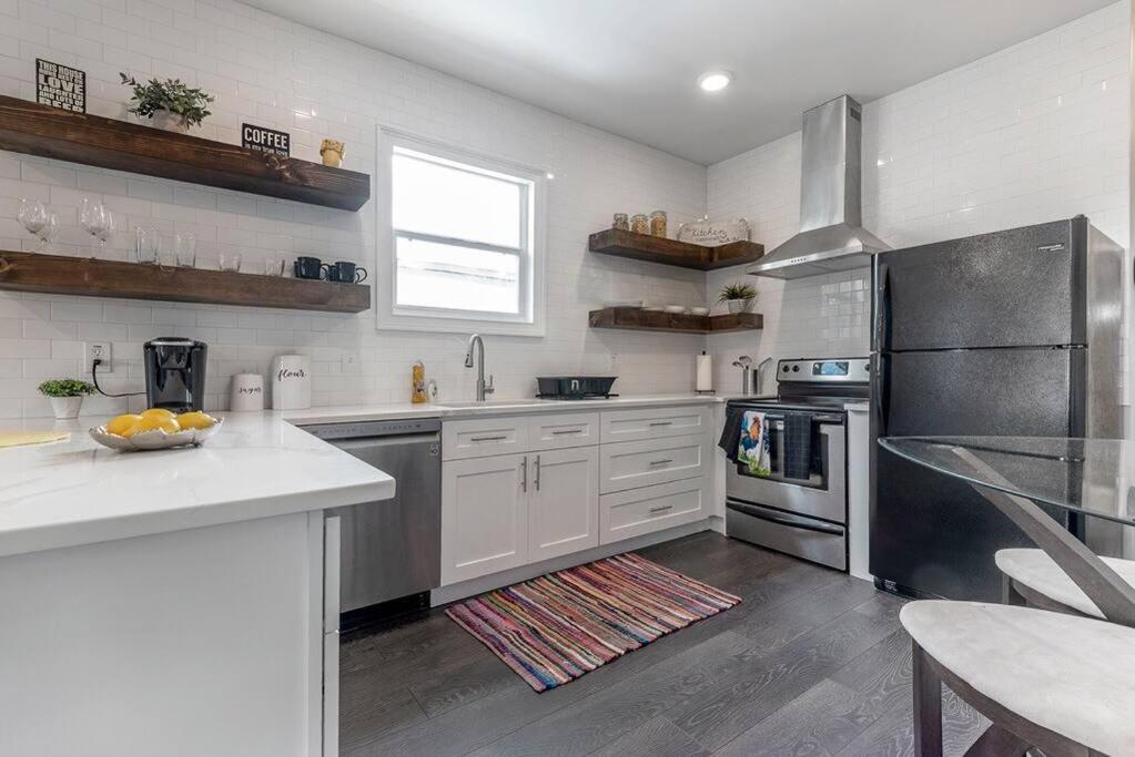 a kitchen with white cabinets and stainless steel appliances at Gambino Getaway Shotgun style apt in the heart of Ybor City in Tampa