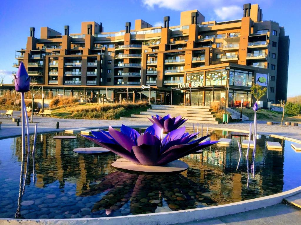 un edificio con flores púrpuras frente a una fuente en Nordelta - Zaduh - en Tigre