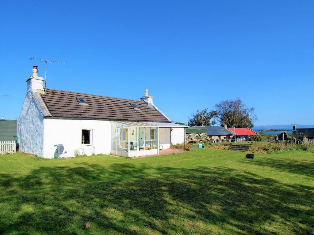 a white house in a field with a yard at Tigh Na Maraiche in Craighouse