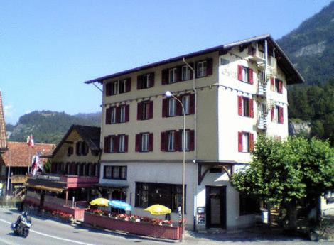 ein großes weißes Gebäude mit Sonnenschirmen davor in der Unterkunft Alpenrose in Innertkirchen