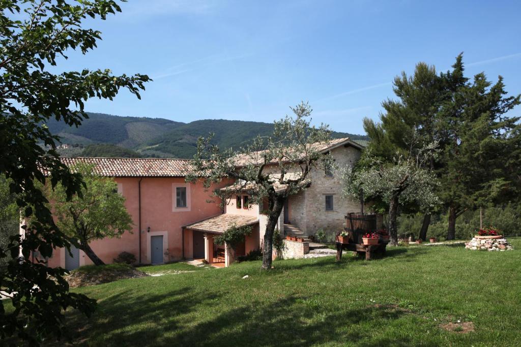 Uma casa italiana com um jardim relvado à frente. em Tenuta San Felice em Giano dellʼUmbria