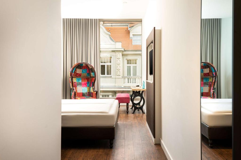a bathroom with two beds and a table in a room at elaya hotel leipzig city center in Leipzig