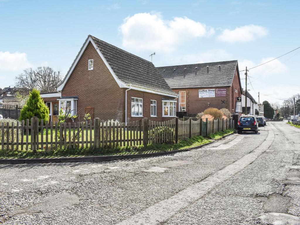 una casa con una valla a un lado de la carretera en Oakfield en Shrewton