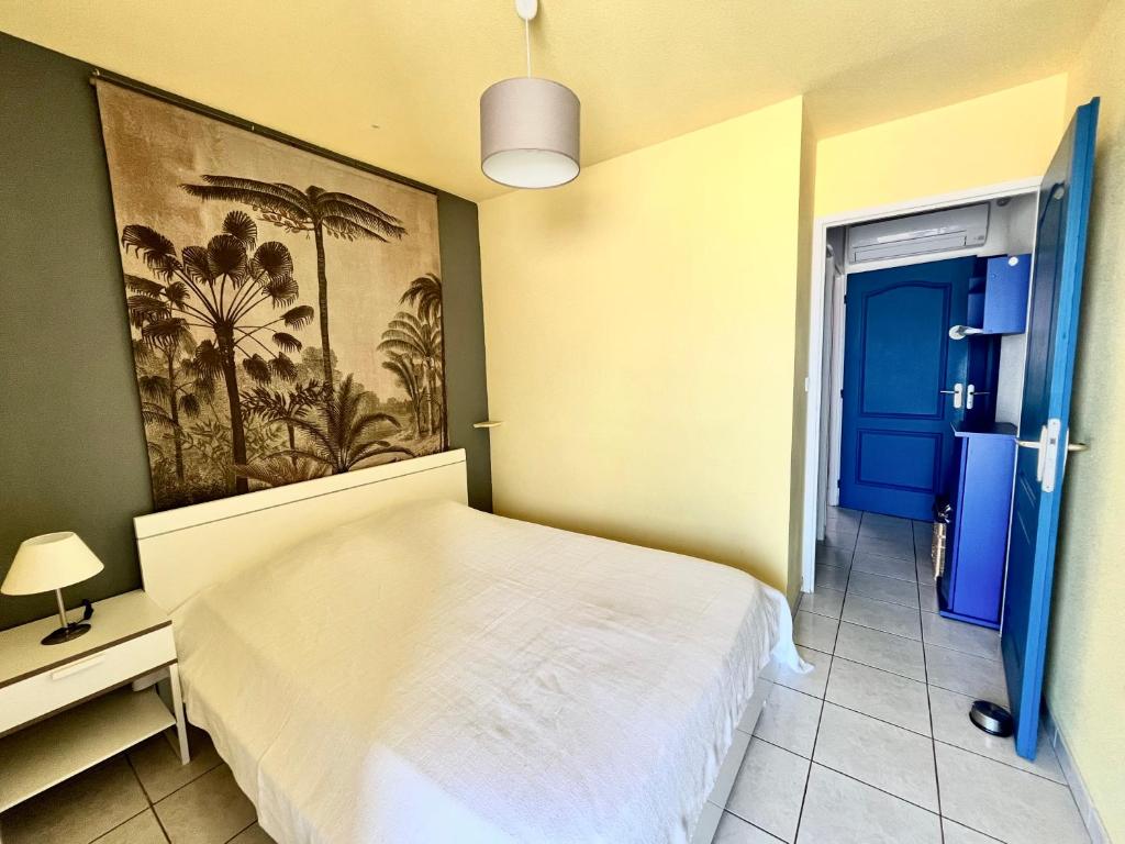 um quarto com uma cama branca e uma porta azul em Barcaresa-Villa Vue Mer Accès Direct Plage - Piscine em Le Barcarès
