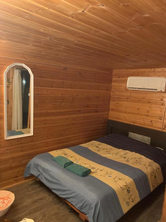 a small bedroom with a bed in a wooden room at בקתה בכרם BH in Nevatim