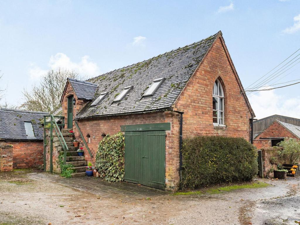 une vieille maison en briques avec une porte verte dans l'établissement The Saddlery, à Shirley