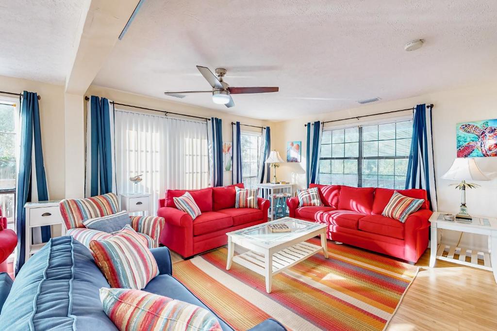 a living room with red couches and a table at Island Palms in St. George Island