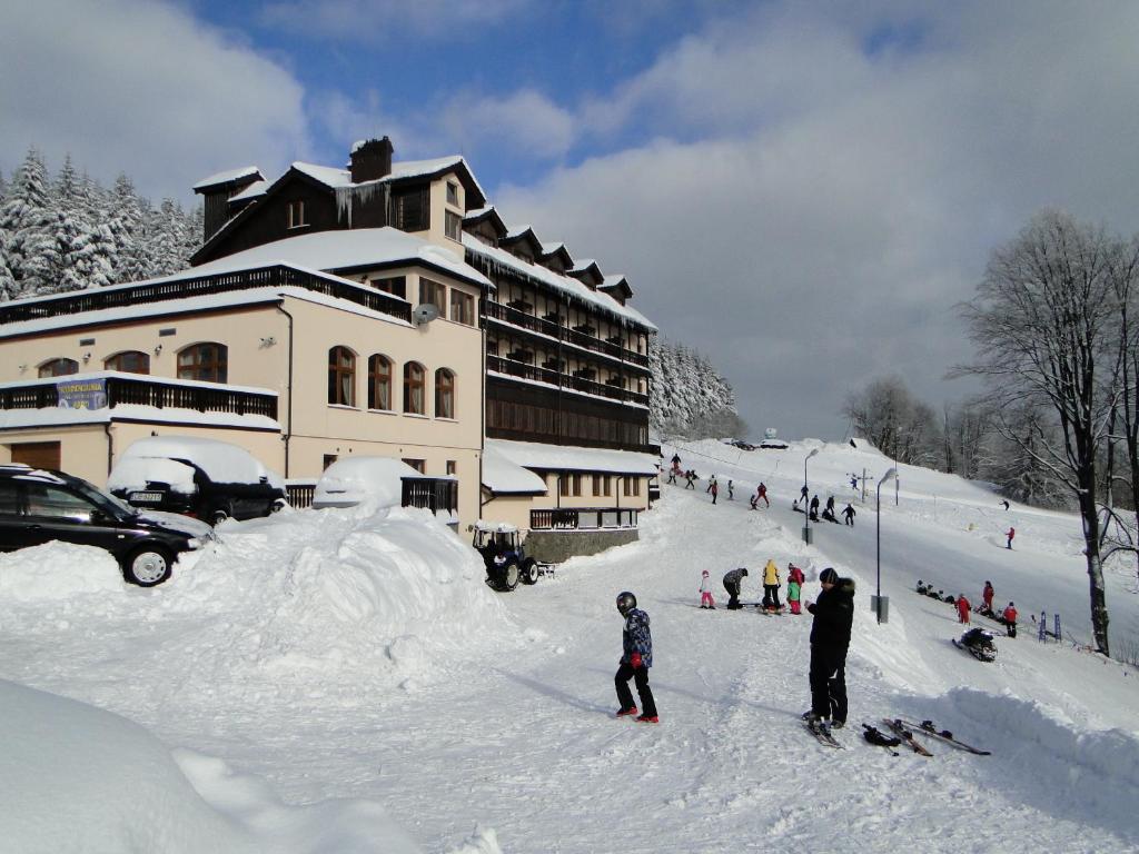 a group of people in the snow in front of a building at Hotel Zieleniec in Zieleniec