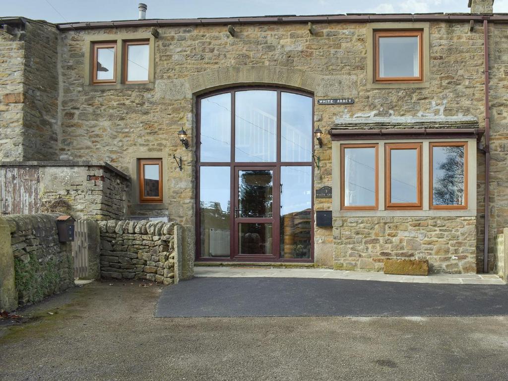 a stone building with a large glass door at White Abbey in Kildwick