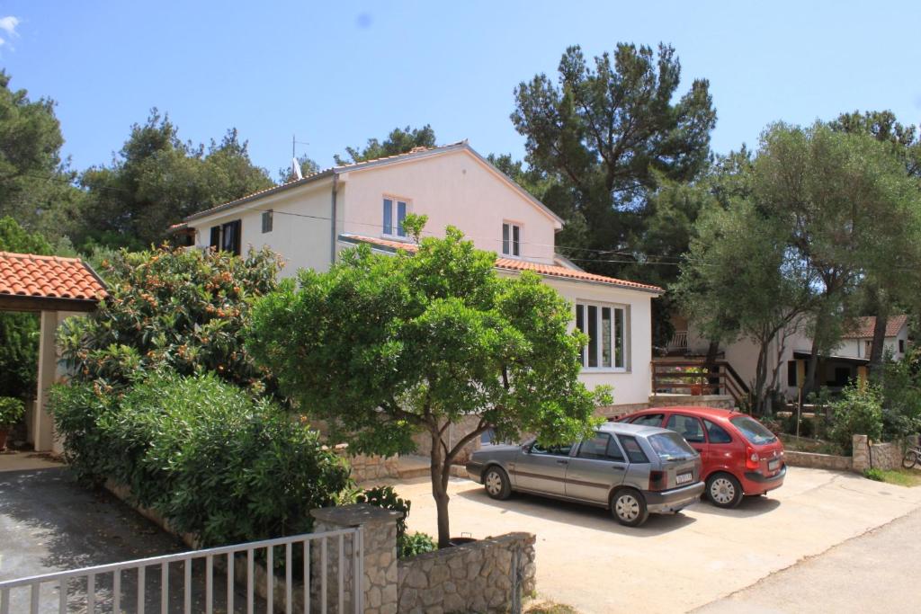 a house with two cars parked in a driveway at Apartments with a parking space Artatore, Losinj - 8007 in Cunski