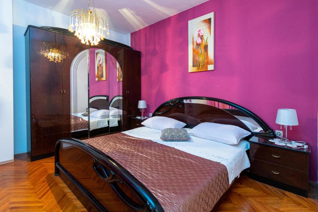 a bedroom with a bed with a pink wall at Apartments with a parking space Bibinje, Zadar - 18275 in Bibinje