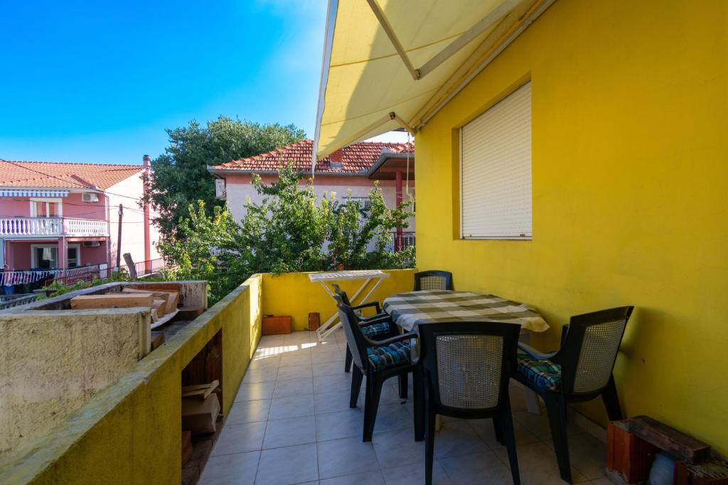 a balcony with a table and chairs on a yellow wall at Apartments with a parking space Bibinje, Zadar - 18275 in Bibinje