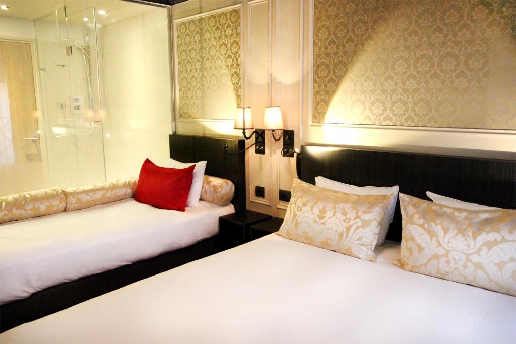 um quarto de hotel com duas camas com almofadas vermelhas em Best Western Le Montmartre – Saint Pierre em Paris