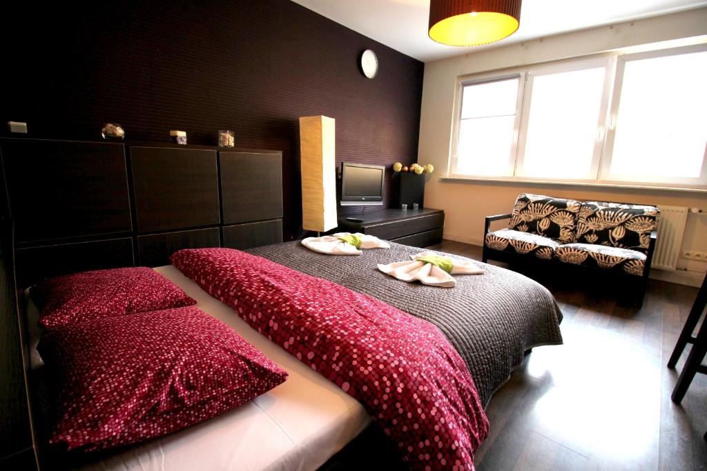- une chambre avec un lit avec des couvertures rouges et un canapé dans l'établissement Happy Apartments Old Town, à Wrocław