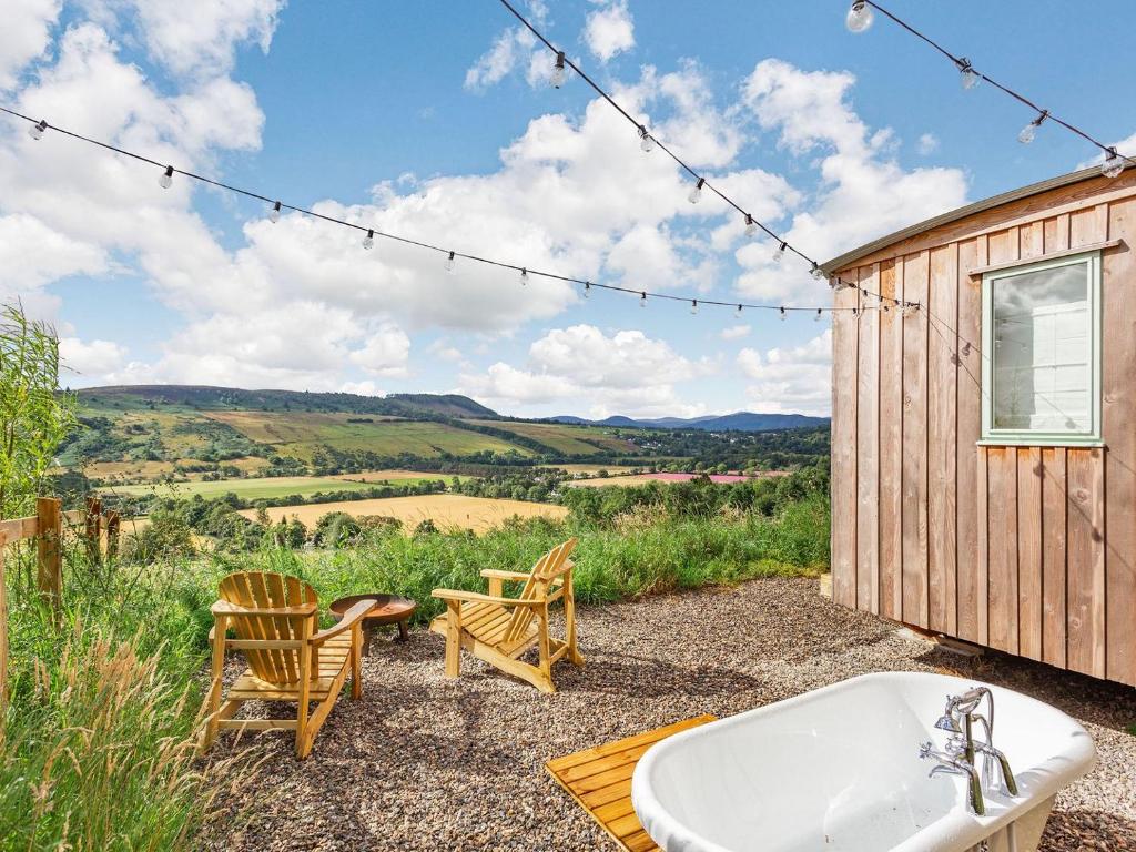 a bathroom with a tub and a table and chairs at Woodside Hut 2 - Uk36106 in Auchterneed