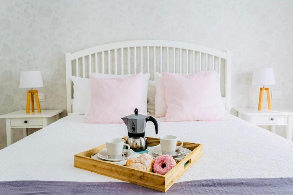 un vassoio con bollitore per tè e ciambelle su un letto di The Little White House, Suite Flower Beach 9 a Playa Honda