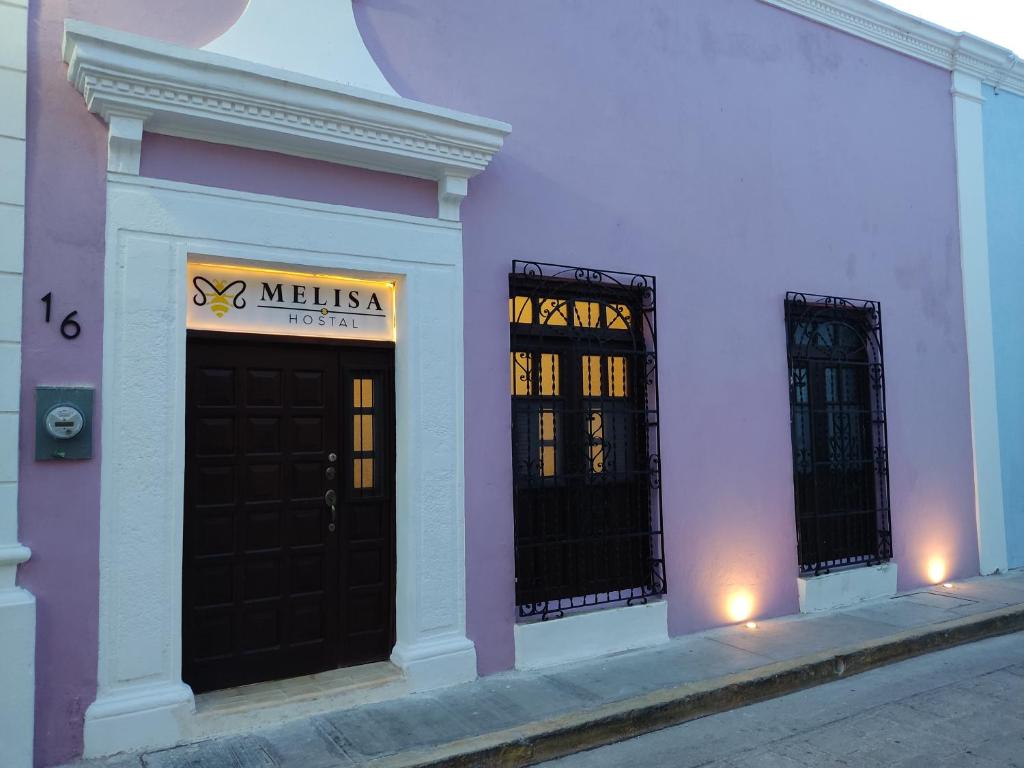 un edificio rosa y blanco con dos puertas negras en MELISA HOSTAL, en Campeche