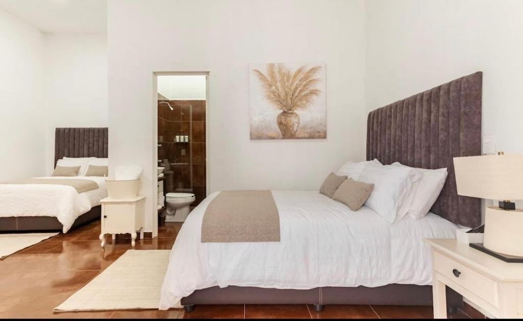 a white bedroom with a bed and a bathroom at Suite Copal in Tecozautla