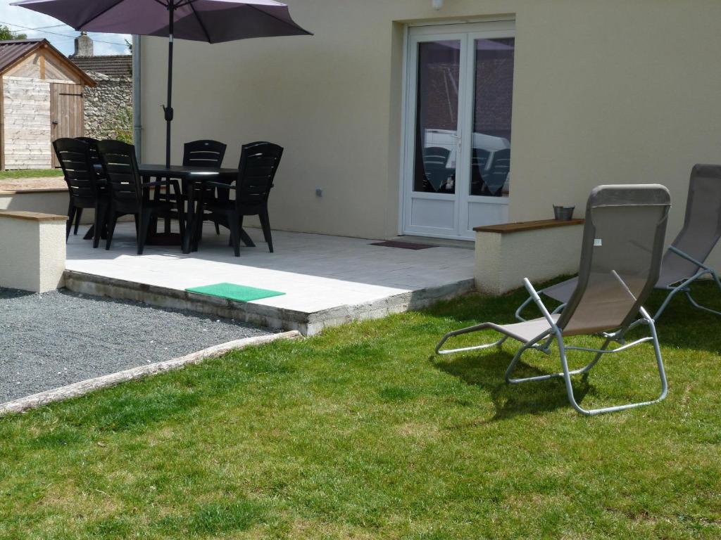 a patio with chairs and an umbrella in the grass at Les Gites De Colliers in Muides-sur-Loire