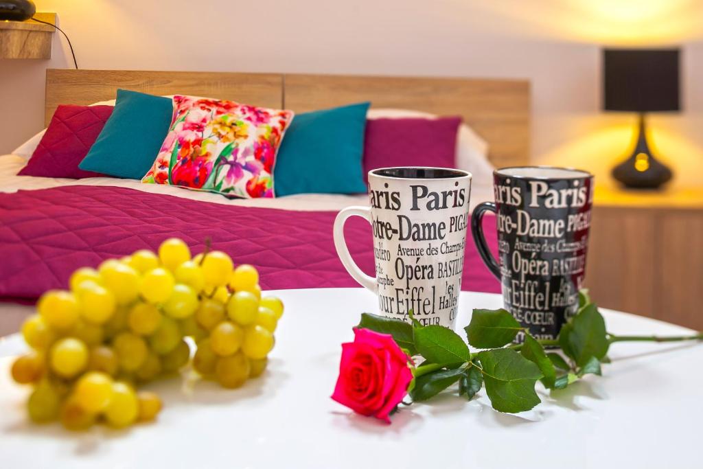 two coffee mugs sitting on a table with flowers at Villa Margo in Białystok