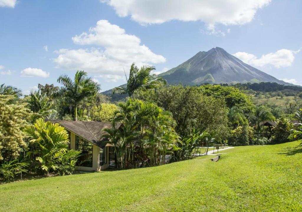 uma casa numa colina com uma montanha ao fundo em Arenal Paraiso Resort Spa & Thermo Mineral Hot Springs em La Fortuna