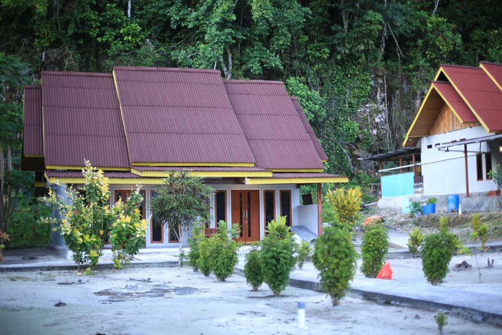 dom z czerwonym dachem i drzewami przed nim w obiekcie Amoryg Resort and Dive Raja Ampat w mieście Pulau Mansuar