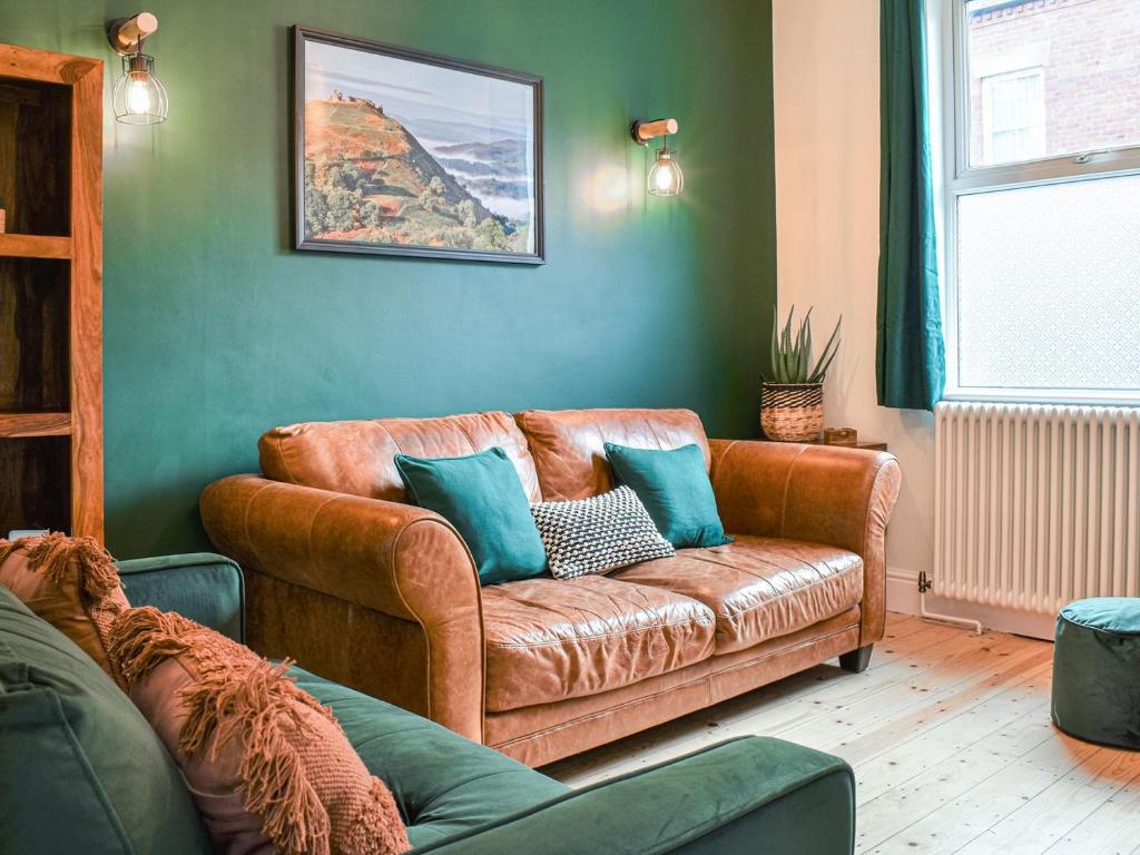 una sala de estar con un sofá de cuero marrón con almohadas azules en Ty Kinik, en Llangollen