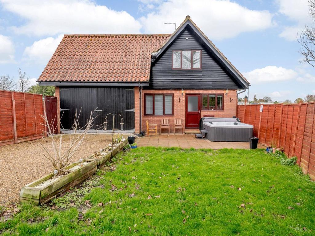 a detached house with a garden and a fence at Riverside Cottage in Loddon