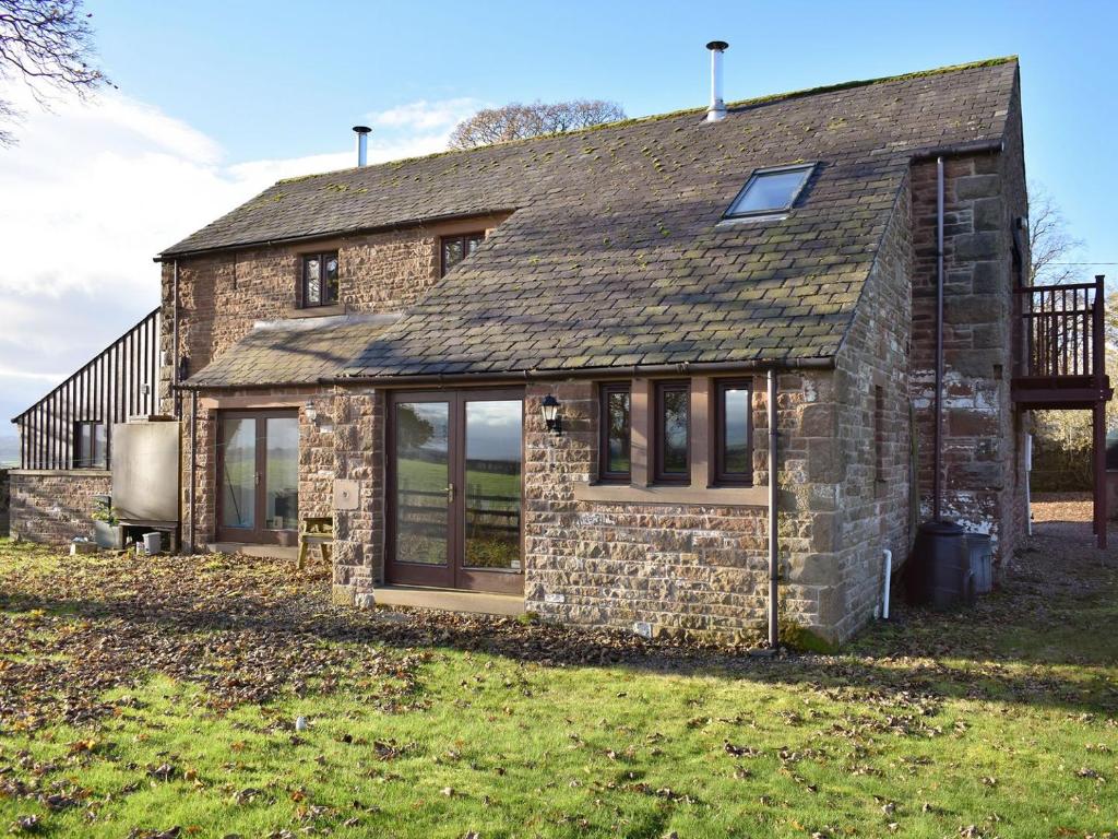 a stone house with windows and a roof at Quarry Cottage in Penrith