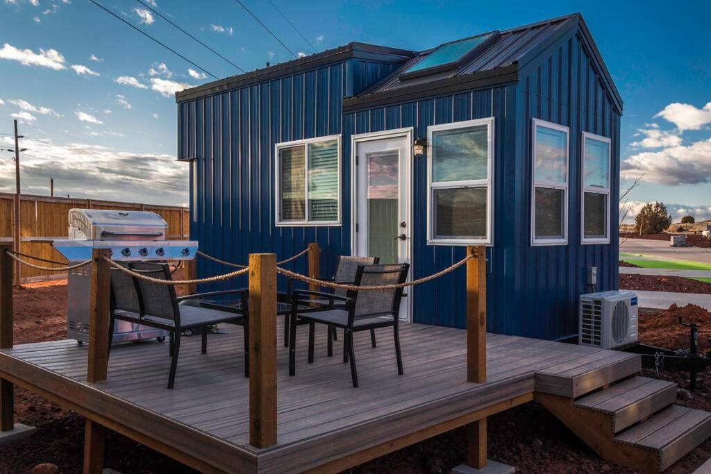 Delightful tiny home conveniently located في Apple Valley: منزل صغير زرقاء مع شرفة خشبية