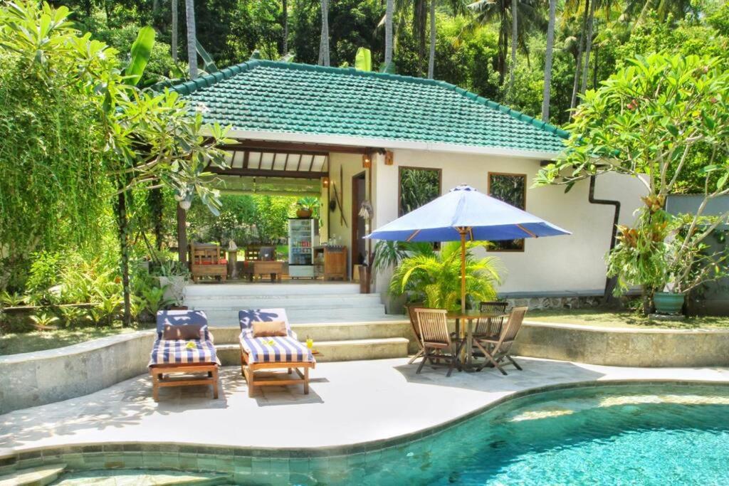 un patio con sillas y una sombrilla junto a la piscina en Villa Serene & Spa Mangsit, en Mangsit