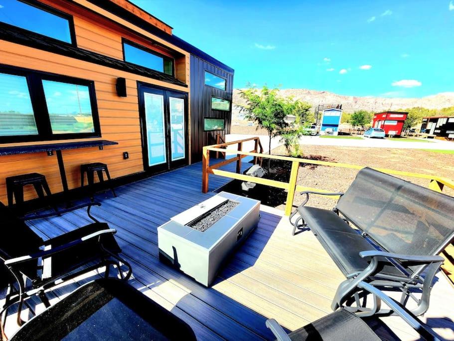 a deck with two chairs and a grill on a house at Designer Modern Tiny Home w All of The Amenities in Apple Valley