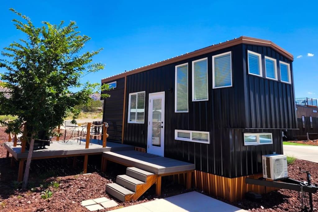 a black tiny house with a porch and a bench at New modern & relaxing Tiny House w deck near ZION in Apple Valley