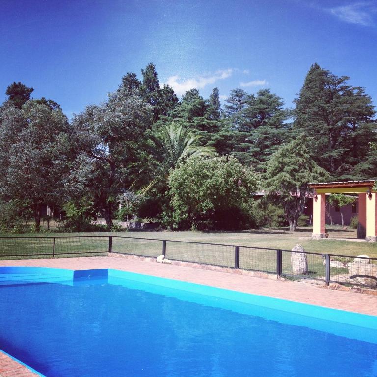a blue swimming pool with a fence and trees at Cabañas Donkaia in La Población