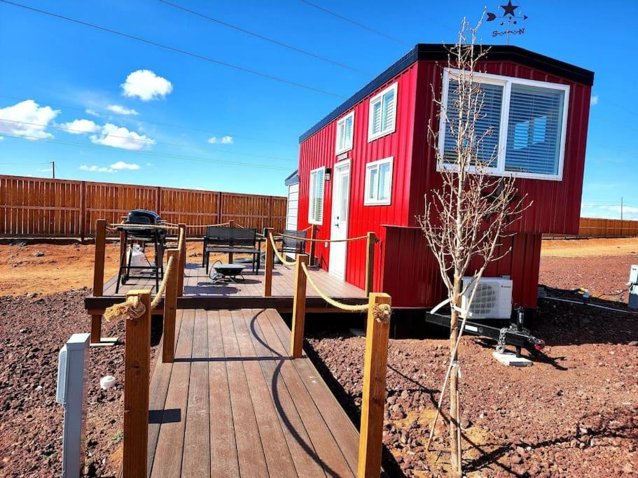 un parque infantil frente a un pequeño edificio rojo en Romantic Tiny home with private deck, en Apple Valley