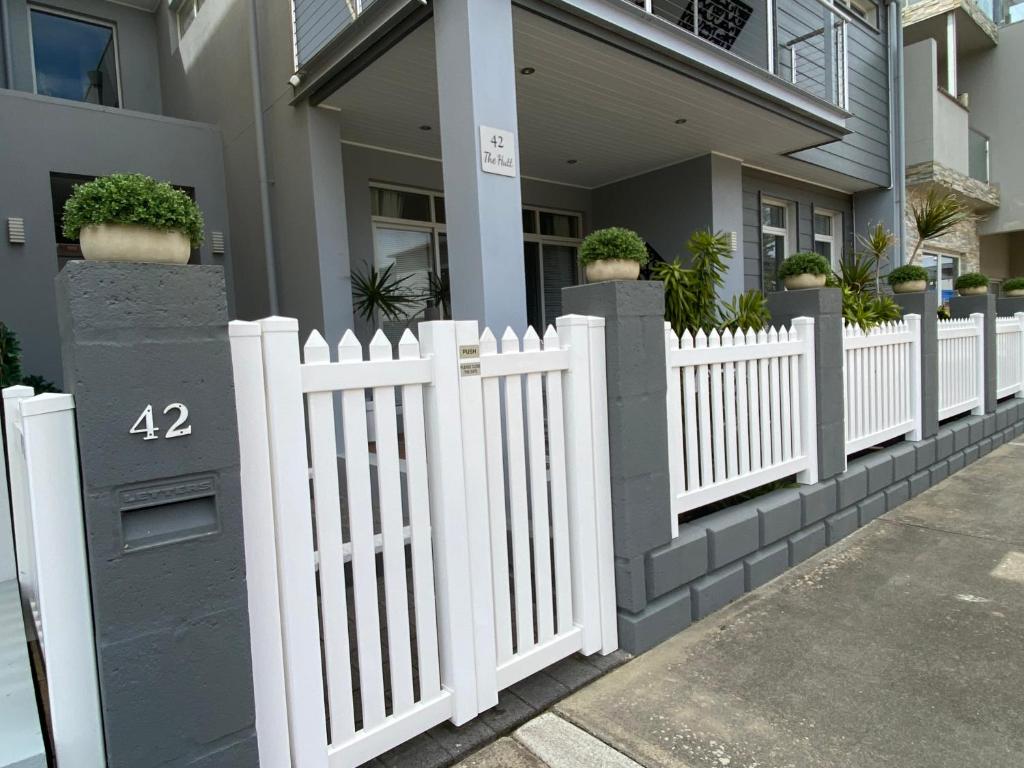 a white picket fence in front of a house at The Hutt on Mandurah Marina in Mandurah