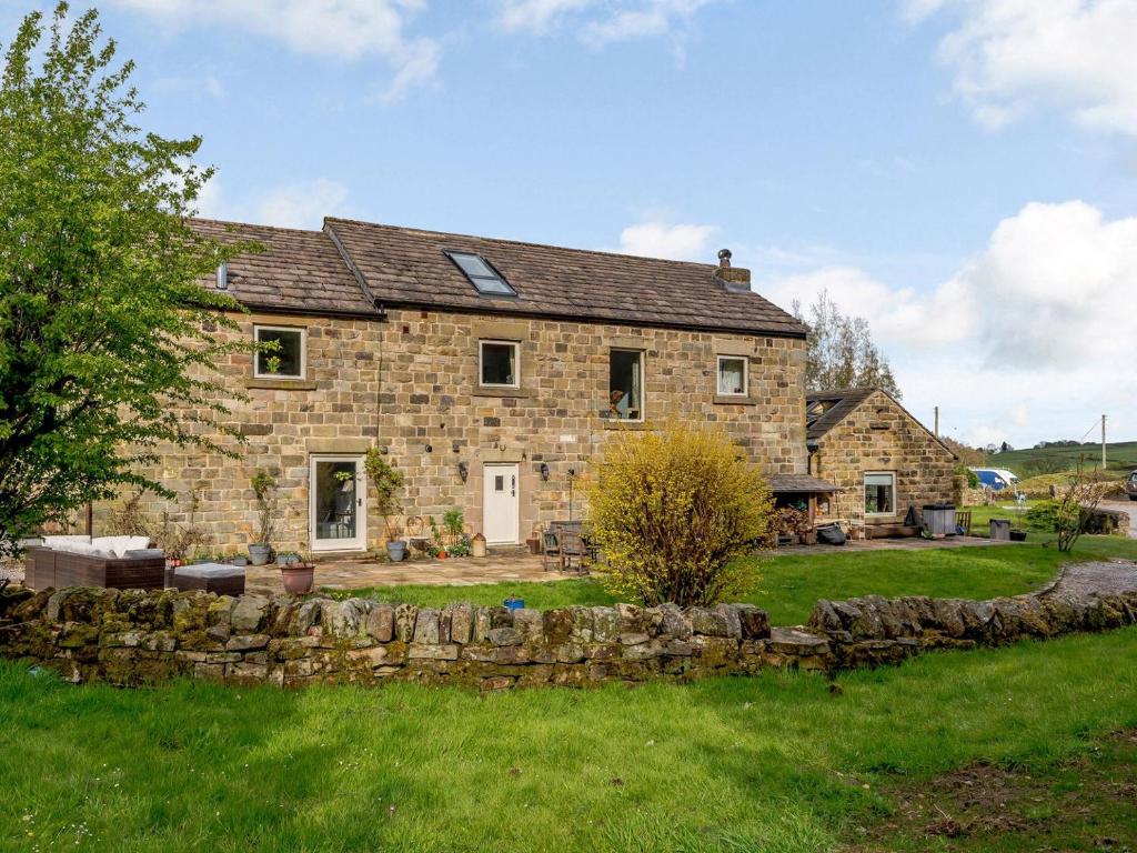 an old stone house with a stone wall at Loadbrook Barn in Ughill