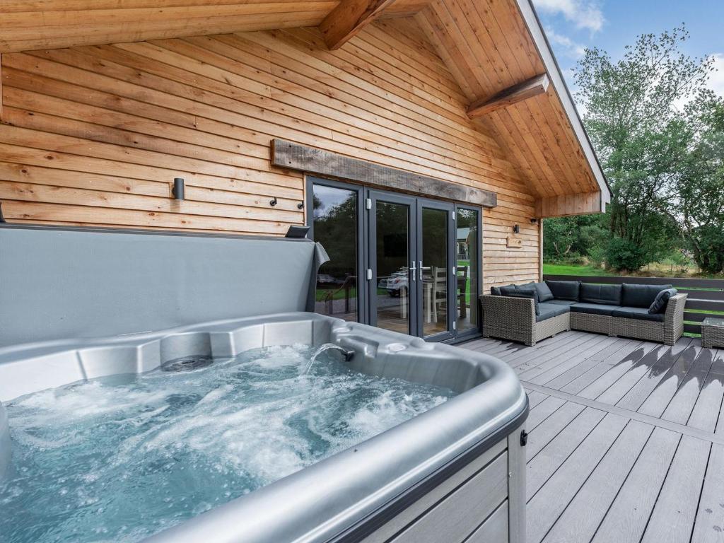 a hot tub on a wooden deck with a patio at Dwrgi - Uk32923 in Cwrt-newydd