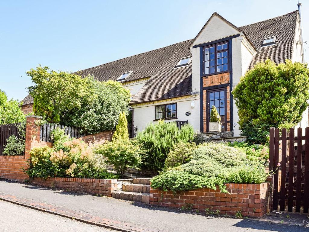 a house with a brick fence and bushes at Saxon Barn in Broom