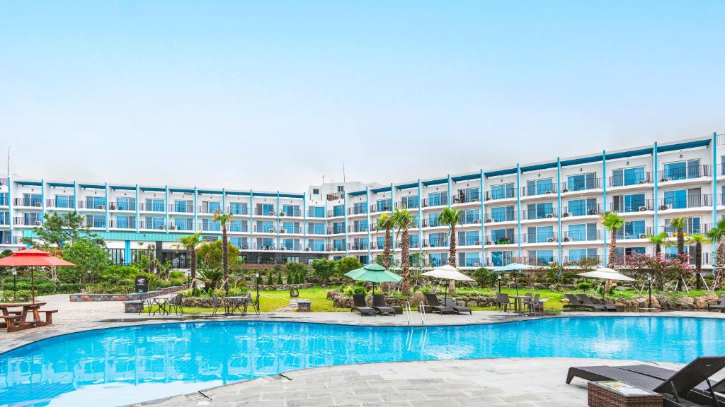 済州市にあるHallim Resortのスイミングプールと大きな建物を併設するホテルです。