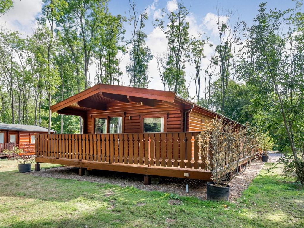 a cabin in the woods with a large deck at Cherry Lodge- Uk37608 in Legbourne