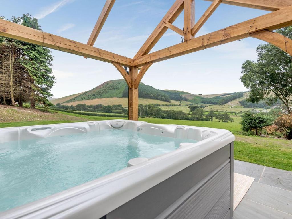 a jacuzzi tub with a view of the mountains at Penshenkin Barn in Llanfihangel-nant-Melan