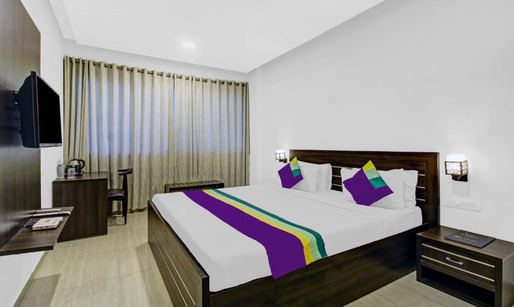 a bedroom with a large bed and a tv at Treebo Tryst Brijinn in Nagpur