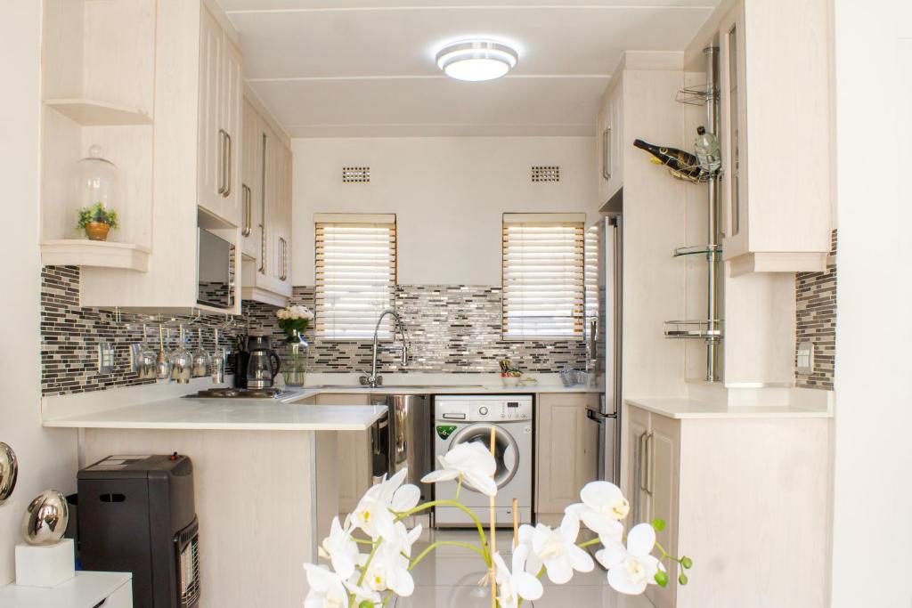 SandtonにあるBeautiful 2 bedroom Apartment near Monte Casinoの白いキャビネットと食器洗い機付きのキッチンが備わります。