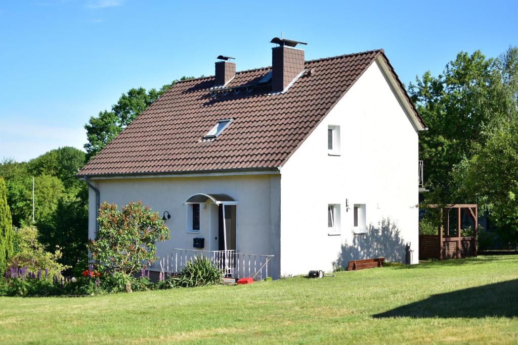 ein kleines weißes Haus mit einem Rasenhof in der Unterkunft Ferienhaus Heideidyll in Bispingen