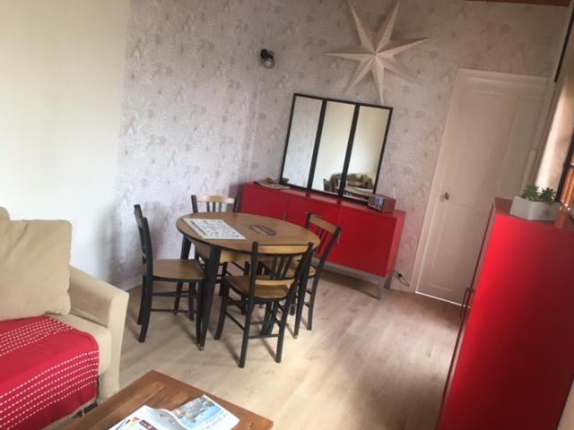 - un salon avec une table, des chaises et une armoire rouge dans l'établissement La jolie petite maison, au Mans