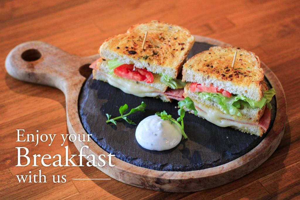 a sandwich on a plate on a wooden table at Grandmas Plus Hotel Seminyak in Seminyak