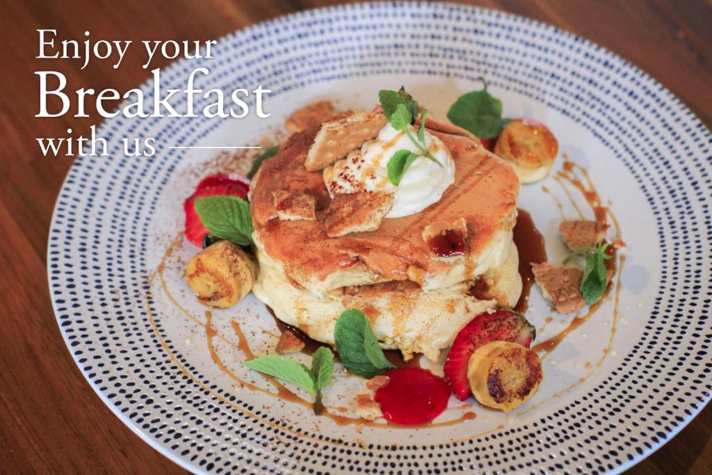 a plate of pancakes with strawberries and whipped cream at Grandmas Plus Hotel Seminyak in Seminyak