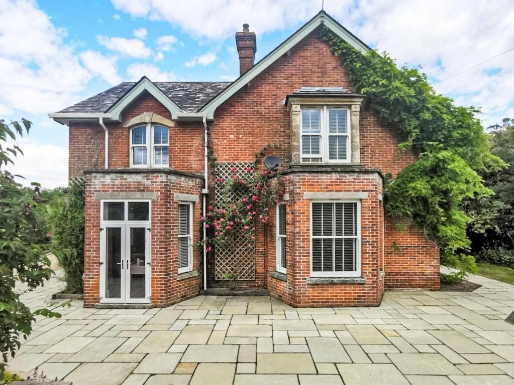 a brick house with a patio in front of it at Blashford Manor Farm House in Ellingham