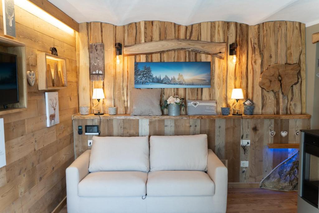 Sofá blanco en una habitación con paredes de madera en LA ROCCIA - CASA VACANZA, en Borgo San Dalmazzo